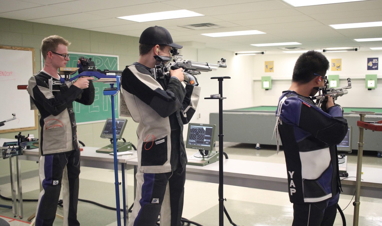Rifle athletes prepare to shoot targets in competition.